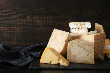 Different kinds of delicious cheese on wooden background