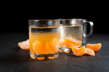 orange drink, tangerines and lemon on a dark background
