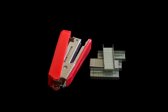 Red stapler and staples steel isolated on black background