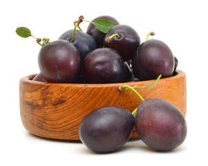 prune plums in wooden bowl on white