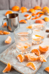 orange drink, tangerines, white cutting board on light gray background