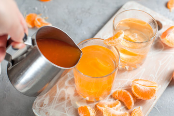 orange drink, tangerines, white cutting board on light gray background