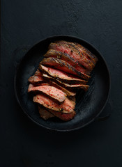 grilled steak in a frying pan on a black  background
