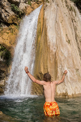 Young handsome man enjoying waterfall