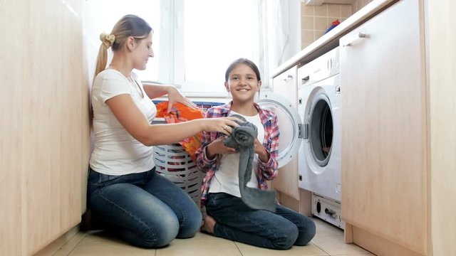 4k video of cute teenage girl helping her mother with laundry