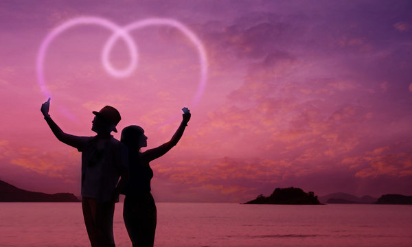 Love Concept, Silhouette of Couple using Smart Phone to making Romantic Heart Shape at Twilight Sea, Valentines Day Background