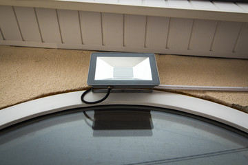 The LED garden searchlight hangs over the entrance to the private house.