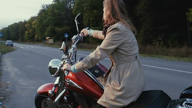 Young girl with brown hair sits on a motorbike near a road.