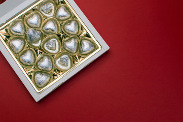Beautiful love concept for Valentines day. Opened sweet box with chocolate heart shaped sweets inside.