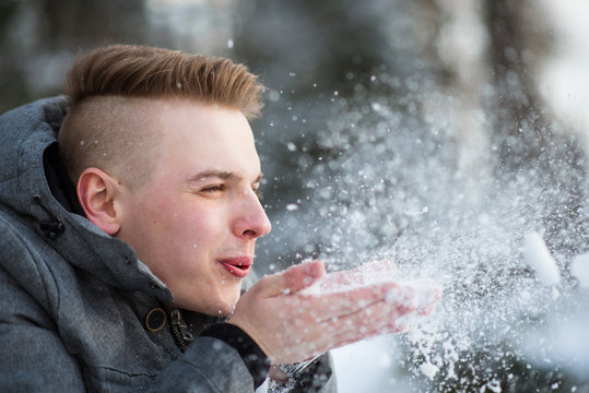 Man blows snow off his hands