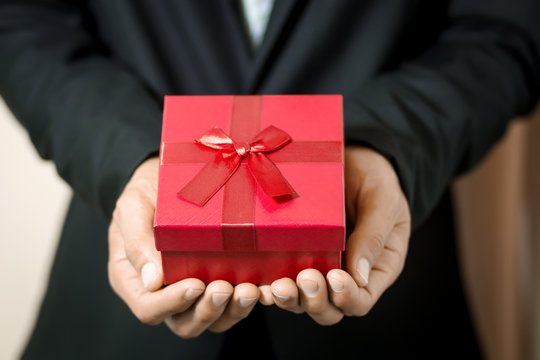 Business Man Hold Red Gift Box In Hands.