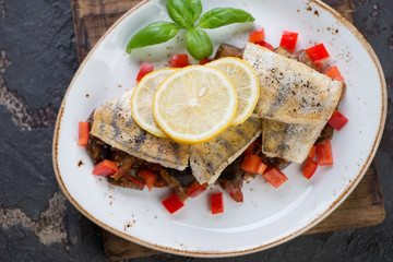 Fried sudak fillet with vegetable saute served on a white plate, top view, horizontal shot