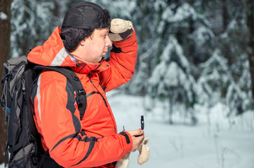 Fototapeta na wymiar a man with a backpack and a compass got lost in a snowy forest