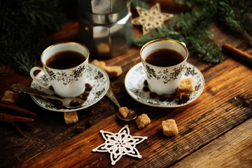 Two cups of espresso with pieces of cane sugar and Italian coffee maker on wooden table.