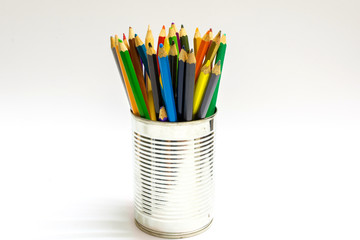 Colorful stationery in can on green background. Colored pencils kept in pencil holder on white background. Color pencils isolated on white background.