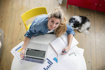 Young beautiful woman works on computer from a home with a laptop on a white desk as a freelancer.Self-employment concept. Top view