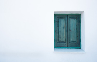 Green closed window on a white wall.