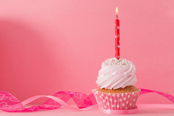 cupcake with candle on pink background