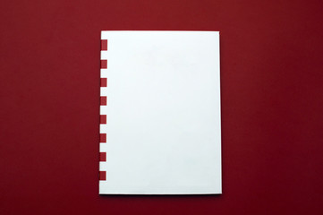 Front view of the white sketchbook with red stripes on the plain red background
