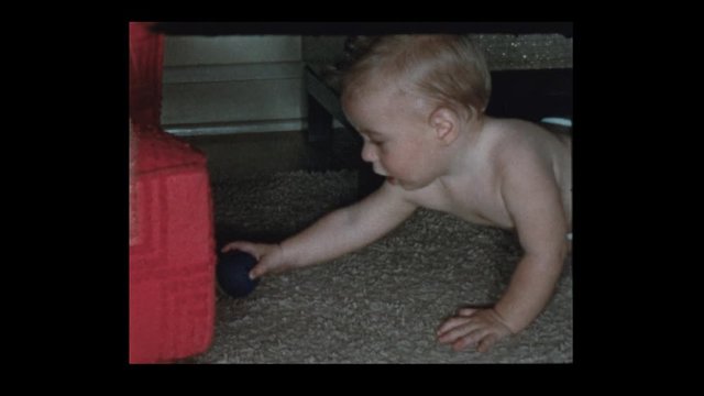 1953 Baby boy in diapers plays with ball