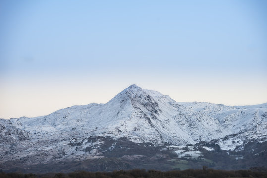 Beautiful Winter sunrise landscape image of Mount Snowdon and other peaks in Snowdonia National Park