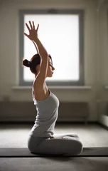 Fototapeten Relaxed young sportswoman doing yoga and meditating in studio © Maksim Kostenko