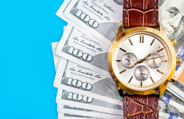 Wrist watch with money on blue background. Top view.