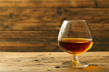 cognac o brandy bicchiere con bevanda alcolica su sfondo legno rustico