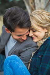 Fototapeta premium Portrait of the young happy romantic couple who sitting in embrace outdoors