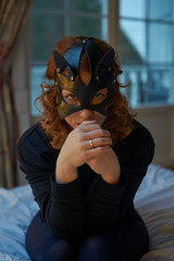 Young redheaded woman in seductive cat's mask