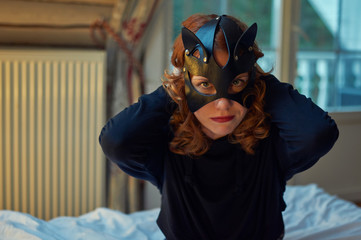 Young redheaded woman in seductive cat's mask