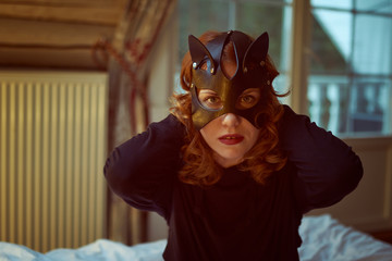 Young redheaded woman in seductive cat's mask