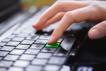 Girl's finger presses thegreen key letter B on the keyboard of the computer. Concept – BE GREEN