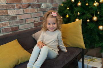 A nice little girl in a gray blank sweatshirt near Christmas tree. Mock up.