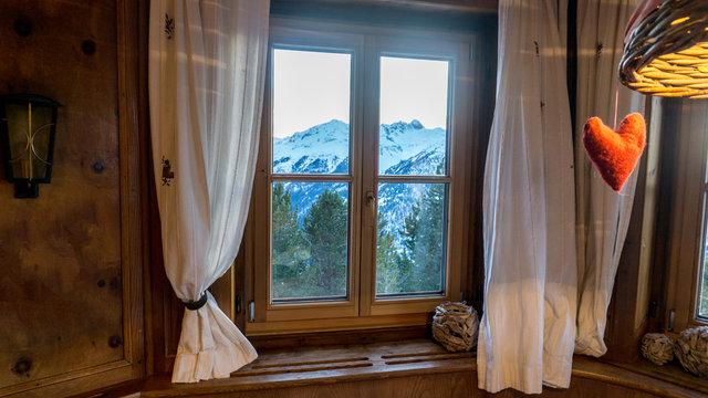 View outside of a wooden cabin window looking to the alps