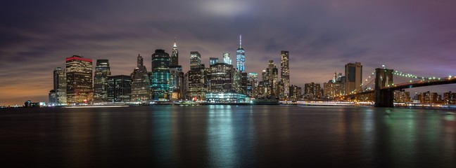 Naklejka premium NEW YORK, UNITED STATES OF AMERICA - APRIL 30, 2017: New York City Manhattan skyline panorama with skyscrapers building at dusk illuminated with lights at sunset.