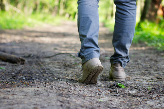 woman with hiking boots is walking on a forest trail.