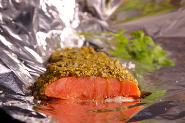 Salmon with pesto and Parmesan sauce, wrapped in foil, ready to bake. Large sea salt and black pepper. Homemade food!