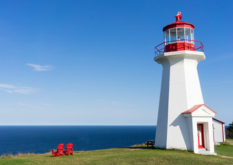 A lighthouse over-looking the blue ocean on the Gaspesie Peninsula of Quebec in Canada on a warm...