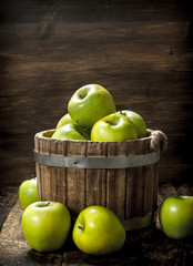 Green fresh apples in a wooden bucket.