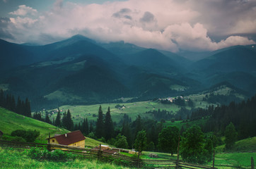 Fototapeta premium Carpathian mountains summer landscape with cloudy sky and village, natural summer travel background