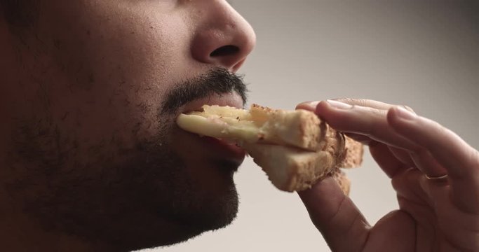Black man eats a sandwich closeup with a streaching cheese