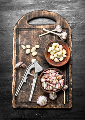 Fresh garlic with a press tool on a wooden board.