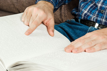 The blind man was reading a book written on Braille. Touch your finger on the braille code. A book with Braille text