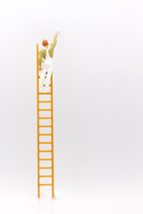 miniature people, mini figure with ladder and white paint in front of a wall