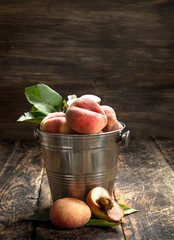Fresh peaches in a bucket with leaves.