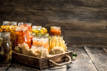 Different preserved vegetables from vegetables and mushrooms in glass jars.