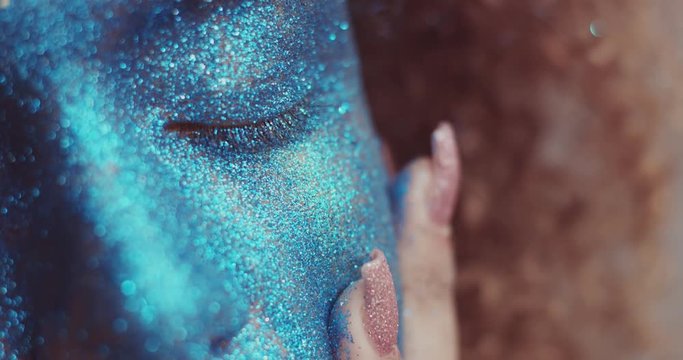 black woman with blond hair and blue glitter face makeup portrait