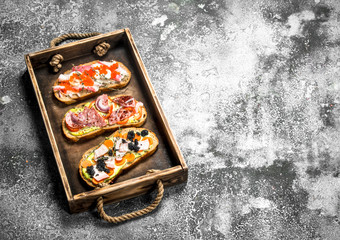 Sandwiches with meat, salami, seafood and fresh vegetables.