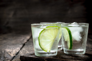 Vodka shots with lime and ice on the board.